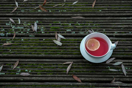 Hot fruit tea with lemon slice in white mug on wooden background, cozy hot winter drink conceptの写真素材