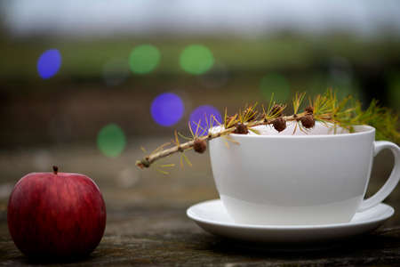 Cup of tea and red apple fruit on colorful bokeh backgroundの写真素材