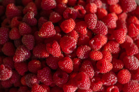 Fresh raspberries in a white bowl on the background of a green grass and autumn leaves