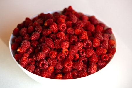 Fresh raspberries in a white bowl isolated on white table backgroundの写真素材