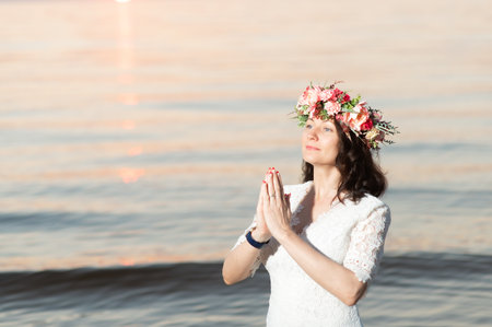 Young woman taking selfie through smart phone while standing at beach during sunsetの写真素材