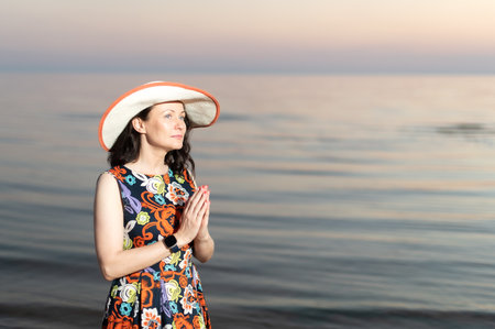 Young woman taking selfie through smart phone while standing at beach during sunsetの写真素材