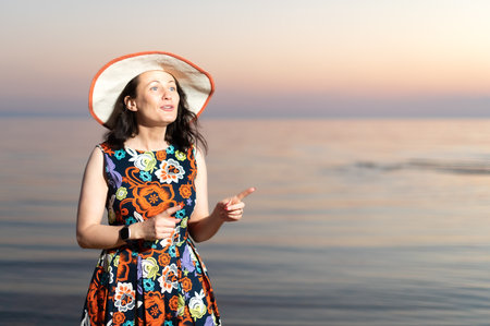 Young woman taking selfie through smart phone while standing at beach during sunsetの写真素材