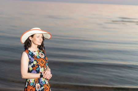 Young woman taking selfie through smart phone while standing at beach during sunsetの写真素材
