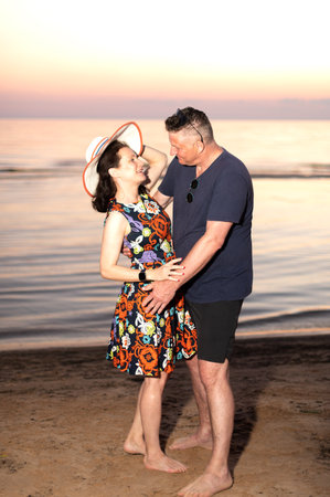 Happy couple- young woman and elderly man dancing on sunset sea backgroundの写真素材