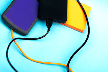 Three external portable hard disk drives isolated on light blue background