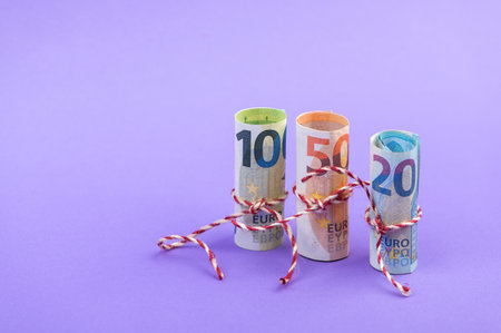 Rolls of 100, 50 and 20 euro money banknotes isolated on light purple backgroundの写真素材