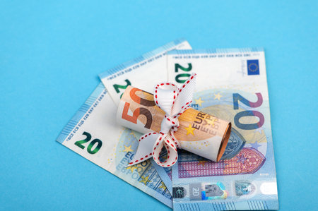 rolled into a roll of 50 euros on a light blue background of 20 euro banknotes.の写真素材