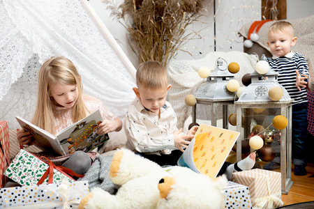 Three children kids read books between Christmas gift boxes in a decorated house.Merry Christmas and Happy Holidays!の写真素材