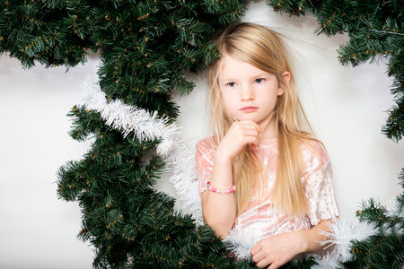 Portrait of beautiful serious little girl in green christmas wreath isolated on white backgroundの写真素材