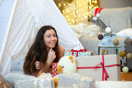Pretty lady woman girl laying on Christmas giftboxes, vintage style decorated home living roomの写真素材