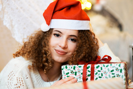 Pretty lady woman laying on Christmas giftboxes  wear knitted pullover and santa hat on bokeh lights...