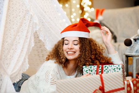 Pretty lady woman laying on Christmas giftboxes wear knitted pullover and santa hatの写真素材
