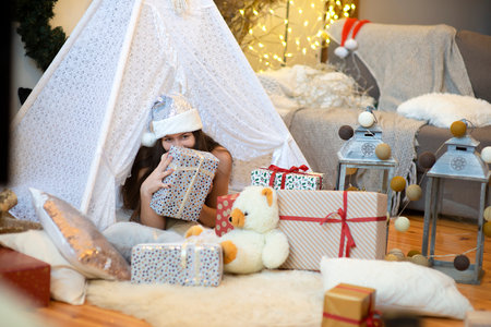 Pretty lady woman girl wear silver color santa hat laying on Christmas giftboxes ,vintage style decorated home roomの写真素材