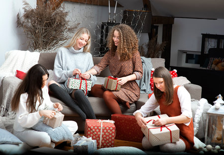 group of young attractive women have fun packing wrapping Christmas presents in a cozy home atmospheの写真素材