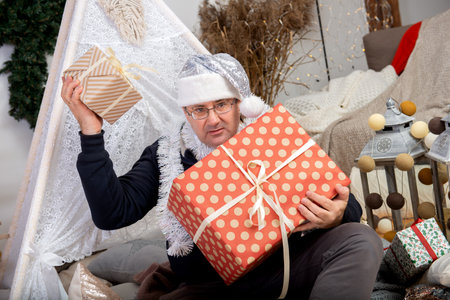 Family grandfather mature man wearing silver santa claus hat holding christmas gift boxの写真素材