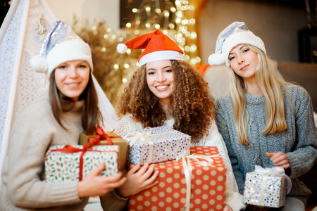 Three sisters beautiful young women celebrate Christmas in a decorated family houseの写真素材