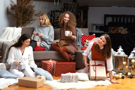 group of young attractive women have fun packing wrapping Christmas presents in a cozy home atmospheの写真素材