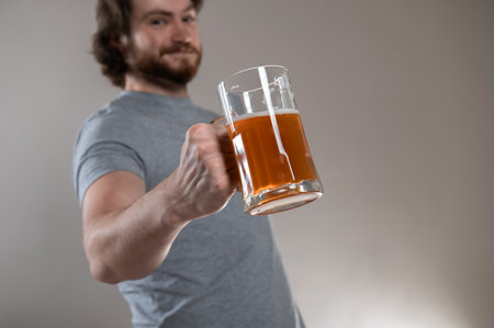 bearded man holding big beer mug over gray background