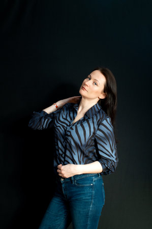 portrait of a young serious brunette on a dark studio backgroundの写真素材