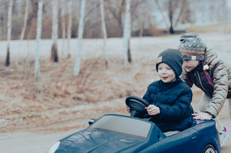 Two happy children playing with big old toy car in countryside, outdoors.の写真素材