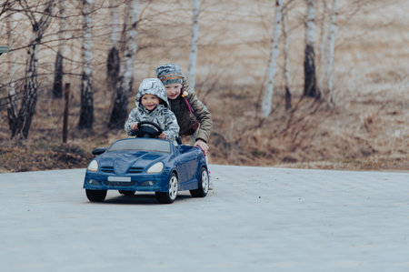Two happy kids having fun drive a blue toy car, road trip adventure conceptの写真素材