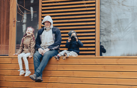 Grandpa with two grandchildren has a good time sitting on the terrace in the backyardの写真素材