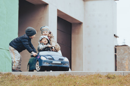 Three happy children playing with old toy car in countryside, outdoors.