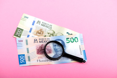 Paper currency of Mexico and magnifier on pink background, mexican pesosの写真素材