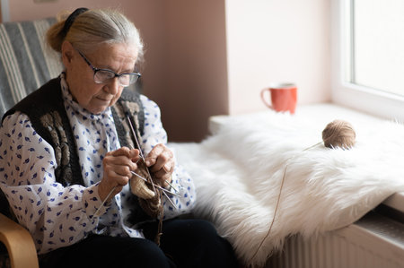 old woman knitting in a nursing home by the windowの写真素材