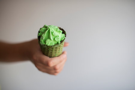ice cream in green waffle cone in hand isolated on gray backgroundの写真素材