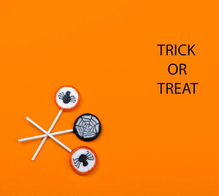 Halloween candy with black spiders and cobweb on orange color background, trick or treatの写真素材