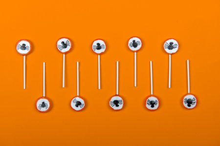 Halloween candy row with black spiders and cobweb on orange color background,top viewの写真素材