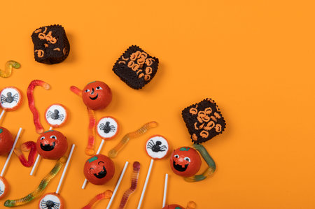 Halloween candy with black spiders,cobweb,smiling pumpkins  and tasty jelly worms on orange color background,top viewの写真素材
