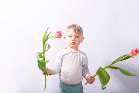 Flowers for your beloved mother. Baby boy holding a tulips flowers. Mothers Dayの写真素材