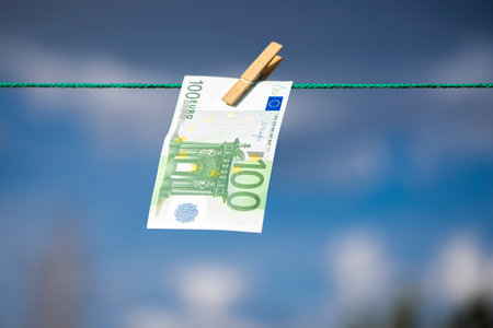 100 euro banknote on a clothesline. Money laundering theme. Blue sky background.の写真素材