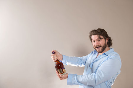 Riga,Latvia- August 4, 2021: A young happy man holding bottle of Courvoisier VSOP Cognac isolated on light gray backgroundのeditorial素材
