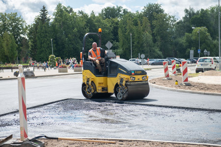 August 4, 2021: Construction site is laying new asphalt road pavement,road construction workers and road construction machinery scene in Sigulda,Latviaのeditorial素材