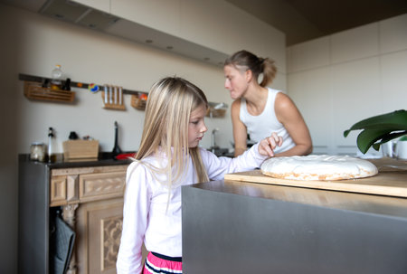Mother with daughter child  preparing sweet dessert cream cake in home kitchenの写真素材