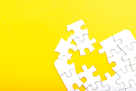 white jigsaw puzzle pieces isolated on a yellow backgroundの写真素材