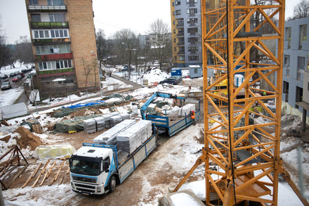 RIGA, LATVIA - FEBRUARY 23, 2021: View of construction site with workers, building materials and a truckのeditorial素材