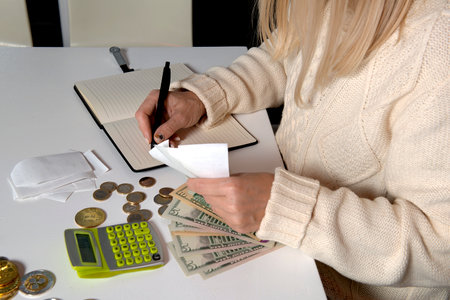Close-up of woman hands , who calculates money with a calculator and writes in a notebook
