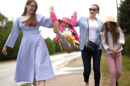 Group of happy family people -two sisters and little girls walking down the city street on a sunny summer dayの写真素材