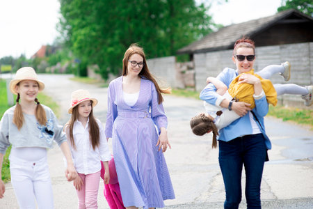 Group of happy family people -two sisters and daughters girls walking down the city street on a sunny summer dayの写真素材