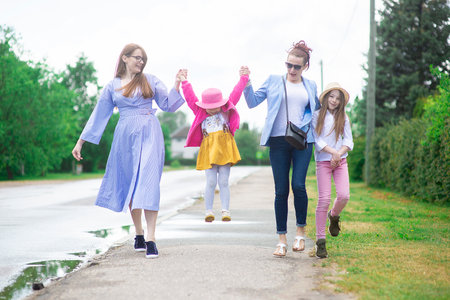 Group of happy family people -two sisters and little girls walking down the city street on a sunny summer dayの写真素材