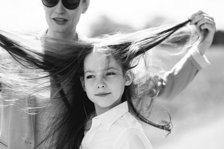 Mother plays with her daughter's long hair on a windy day.の写真素材