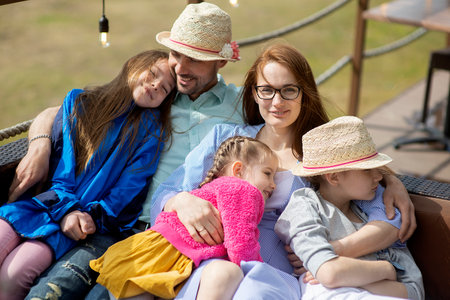 Happy family- mother,father and three children daughter relaxes on outdoor terrace summer restaurantの写真素材