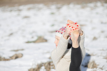 Close-up of bare foot young attractive woman practicing yoga on snowy fieldの写真素材