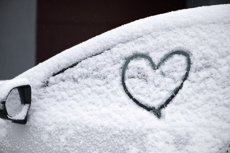 Lovely heart symbol drawn by hand on snowy car window at day light. Christmas and New Year conceptの写真素材