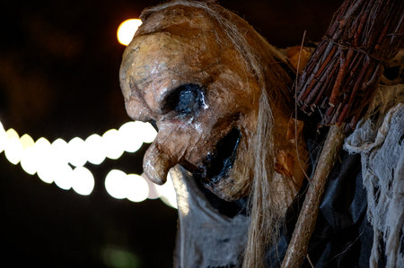 Witch with a broom and a monster face on a dark halloween horror night, bokeh light backgroundの写真素材